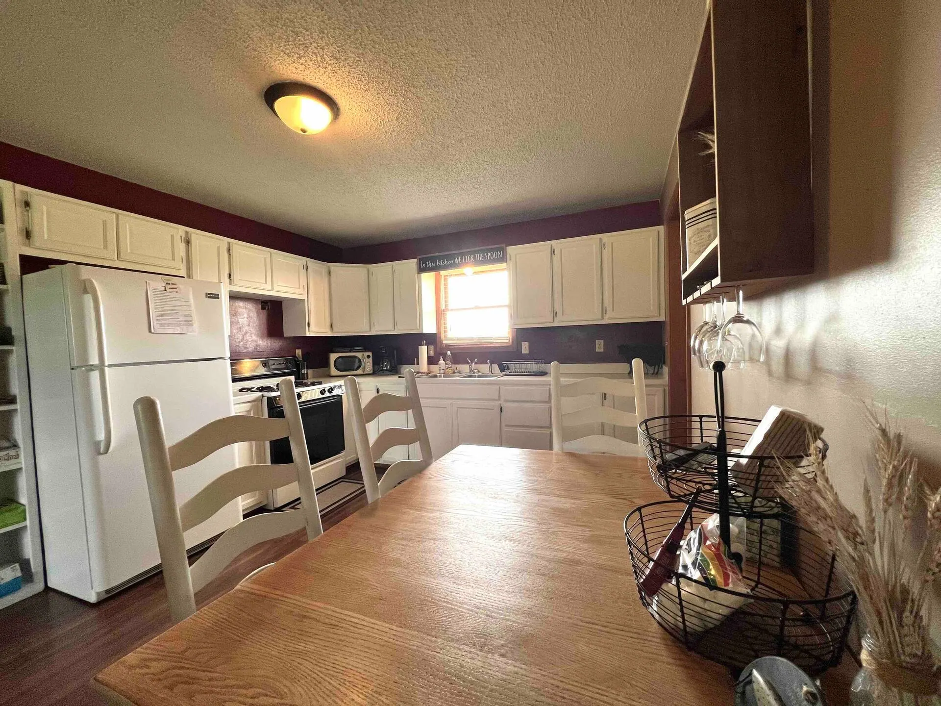 Kitchen and dining area with a wooden table and ladder-back chairs beside the counter